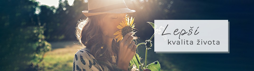 Mladá žena v klobouku voní ke květu slunečnice.